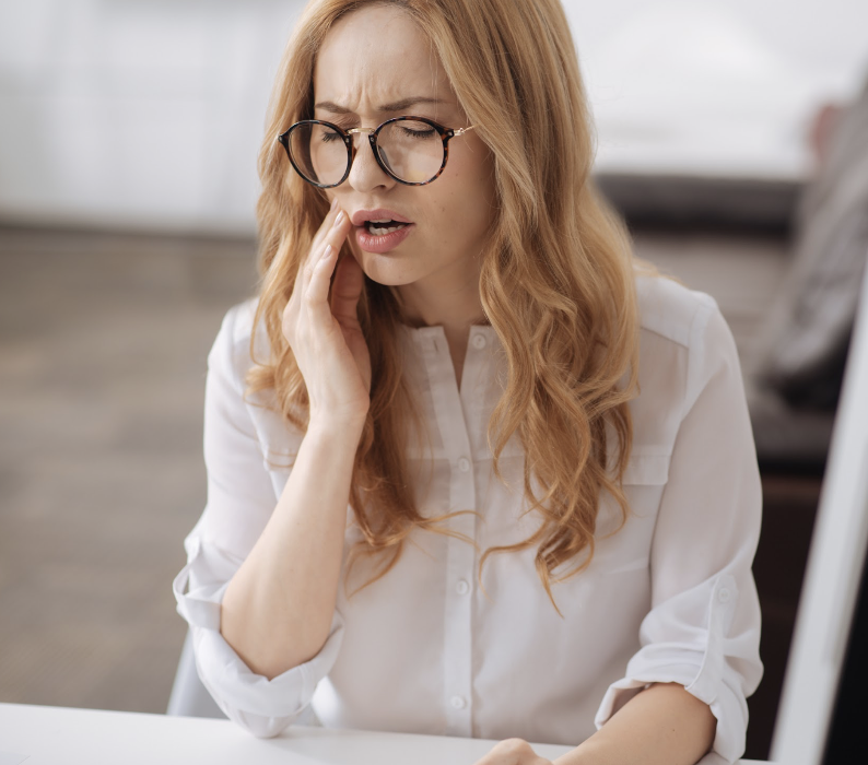 woman holding jaw from tooth pain before an extraction