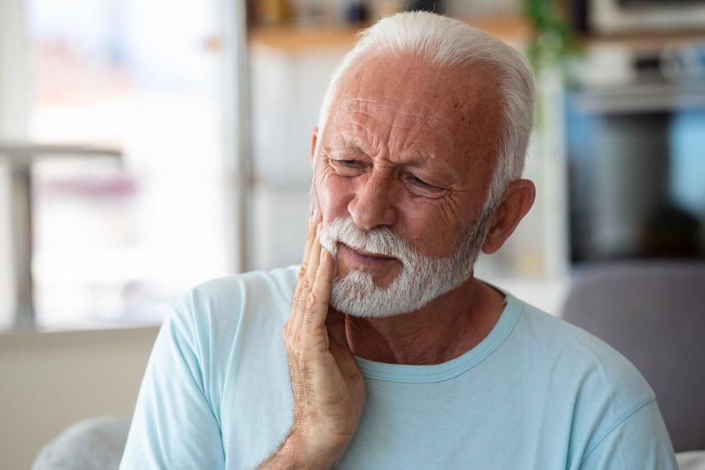 man holding jaw from tooth pain during an emergency