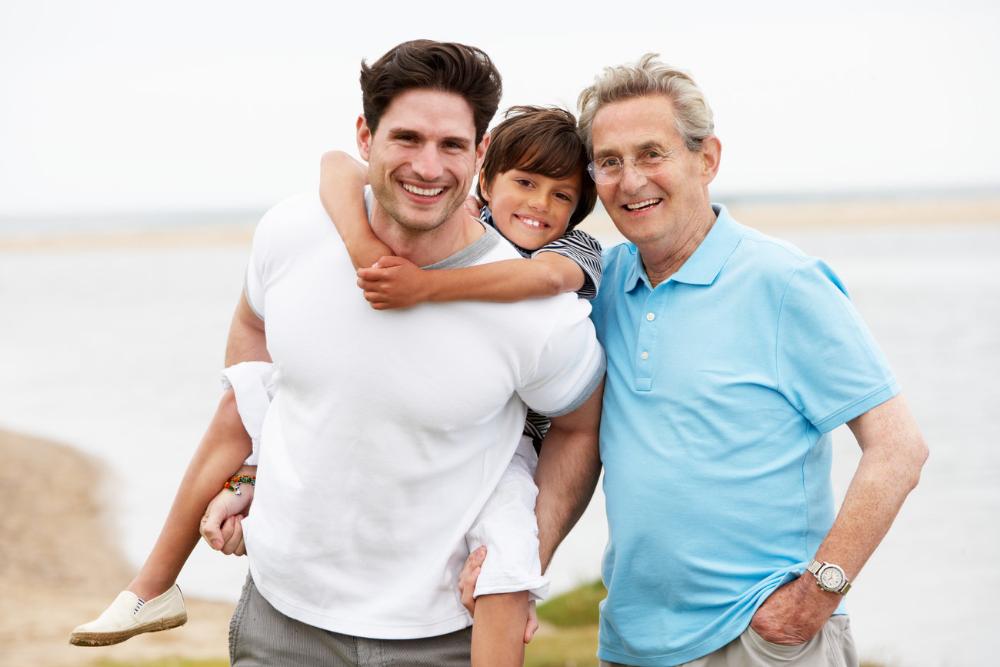 Dad, son, and grandpa smiling near beach