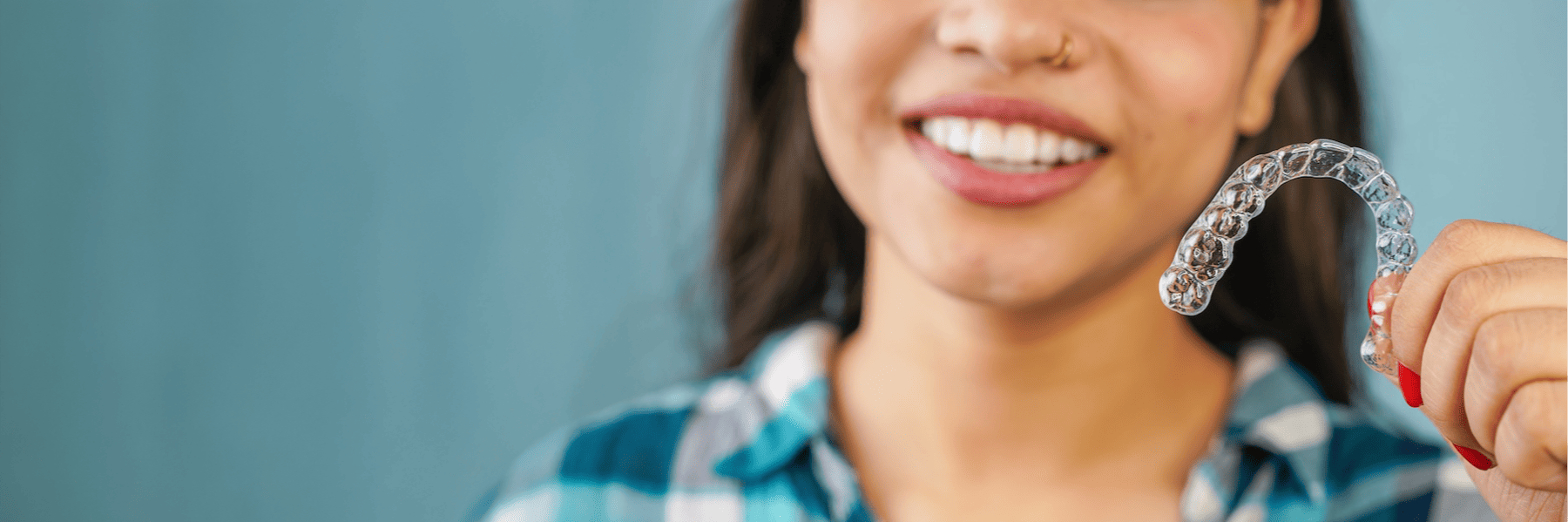 Smiling brisbane city woman holding a clear dental aligner
