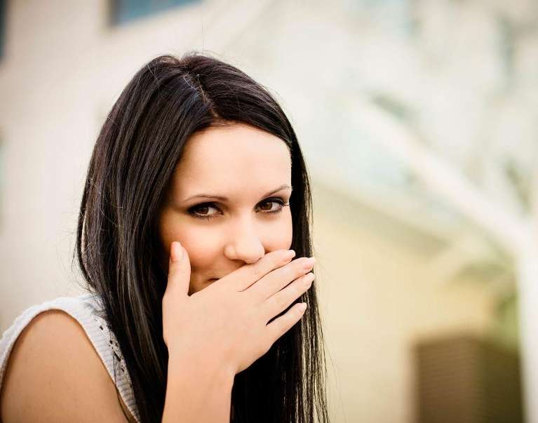 woman covering her mouth with hand to hide bad breath