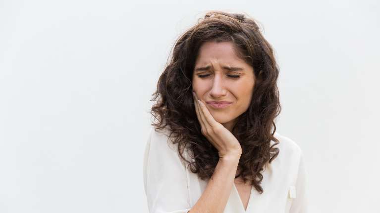 woman holding jaw from dental pain during an emergency in brisbane