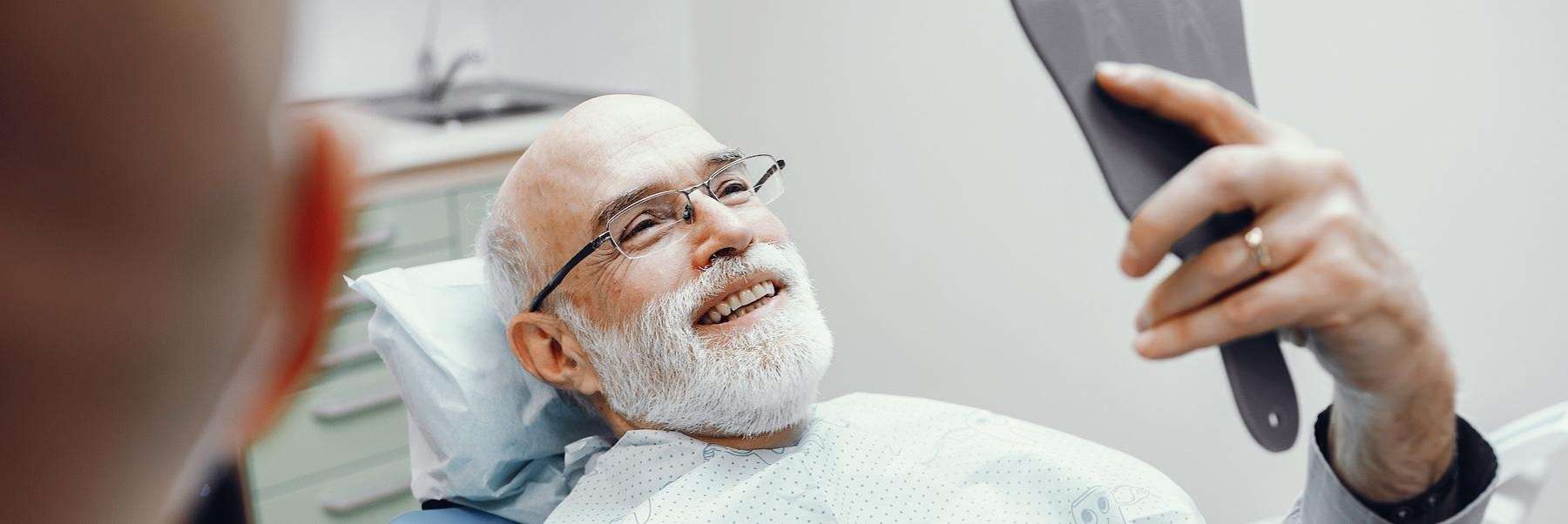 brisbane man smiling in dental mirror after getting dental implants 